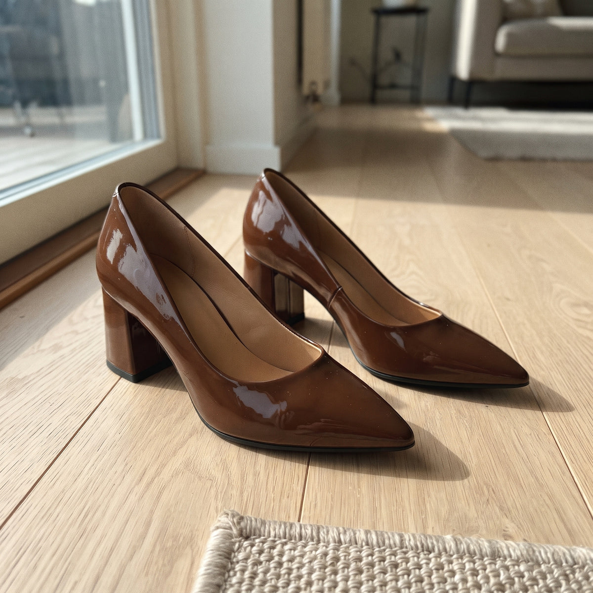 Pair of coffee brown patent leather block heel pumps on light wooden floor