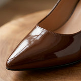Close-up of coffee brown patent leather pointed toe pump showing glossy finish and stitching
