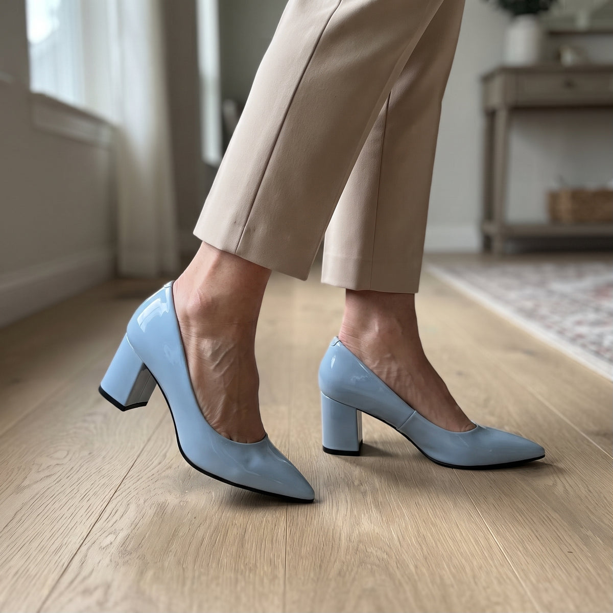 Woman wearing ECADRA baby blue patent leather block heel pumps with beige trousers on wooden floor.