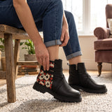 Woman wearing ECADRA Street Mode boots with playing card print panel and cuffed jeans, seated indoors