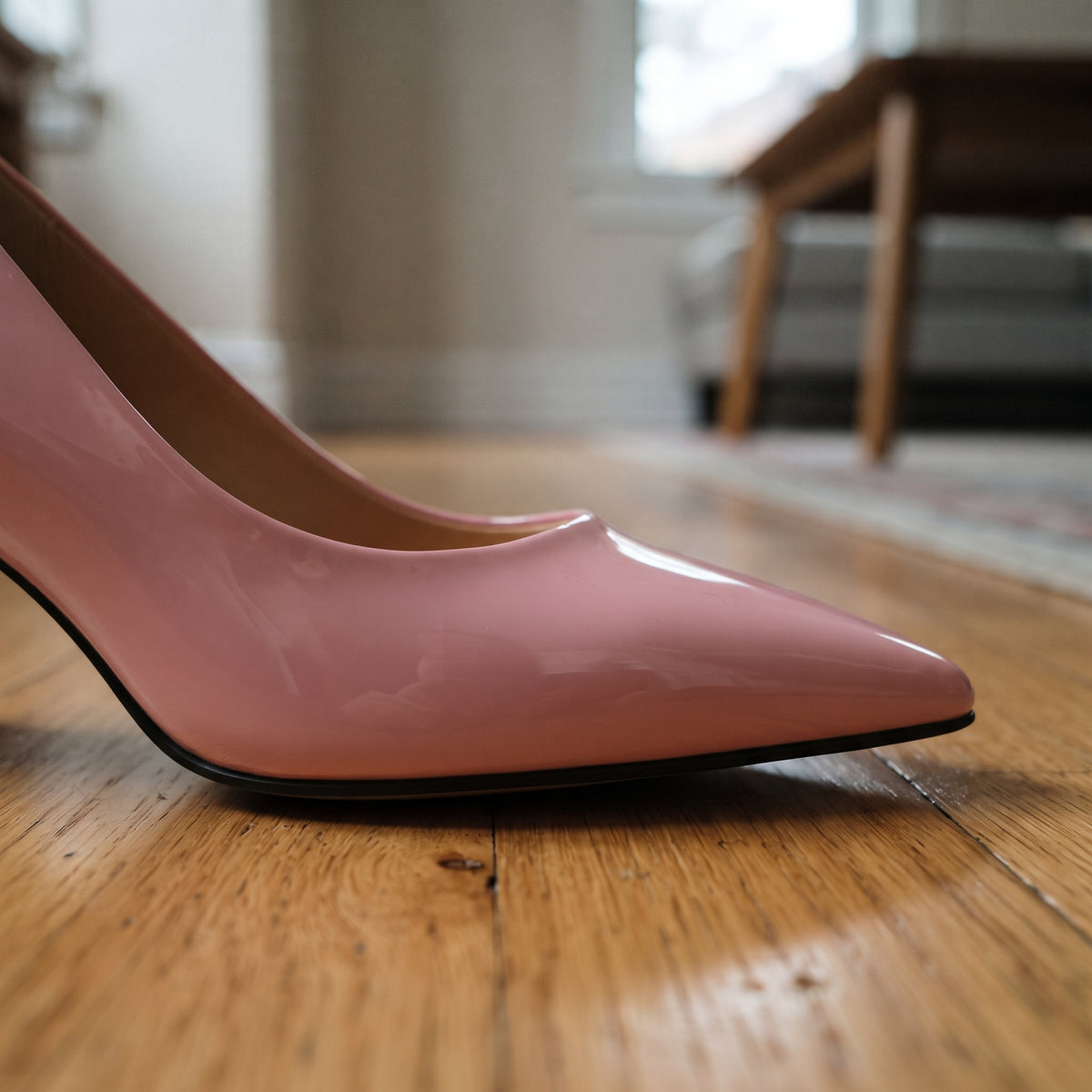 Side close-up of ECADRA pink patent leather pointed toe pump on wooden floor showing glossy finish