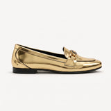 Side profile view of a metallic gold patent loafer with a black-accented buckle on a clean white backdrop.