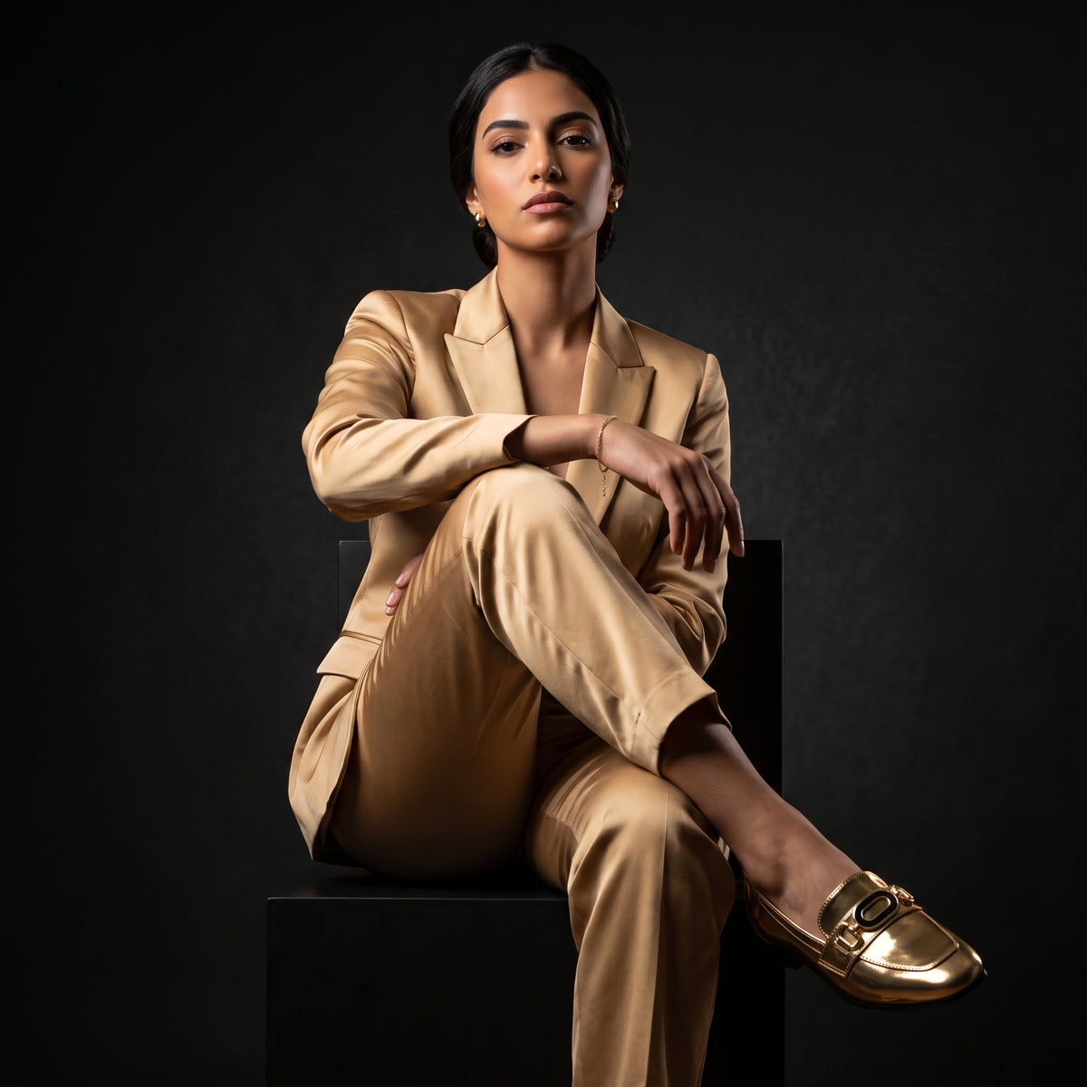 Model wearing a luxury golden satin suit posing in metallic slip-on loafers.