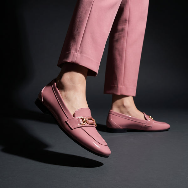 Woman walking in dynamic motion wearing glossy rose patent ECADRA loafers with matching rose trousers.