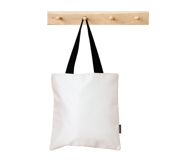 White tote bag with black straps hanging on a wooden rack against a white background