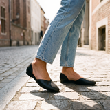 Close-up of black open-side d'Orsay Wink Flats worn with jeans on cobblestones | ECADRA