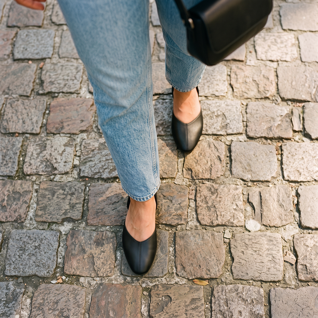 Overhead view of black open-side Wink Flats worn with jeans on cobblestone pavement | ECADRA