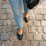 Overhead view of black open-side Wink Flats worn with jeans on cobblestone pavement | ECADRA