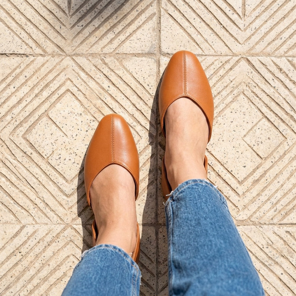 Overhead view of tan open-side Wink Flats worn with cropped jeans on tiled pavement | ECADRA