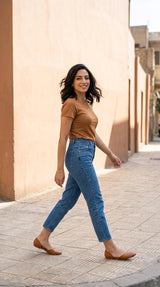 Side view of a woman walking in tan Wink Flats and cropped denim jeans on a sunlit street | ECADRA
