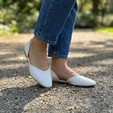 Close-up of white open-side d'Orsay Wink Flats worn with blue jeans on a park path | ECADRA