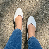 Overhead view of white open-side Wink Flats worn with blue jeans on a park path | ECADRA