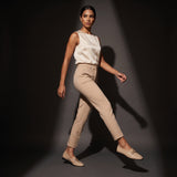 Woman walking forward in dynamic motion wearing glossy beige patent ECADRA loafers with matching beige attire.