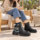 Woman wearing ECADRA Street Mode Nautical Moonlit boots with jeans, seated on outdoor patio holding coffee