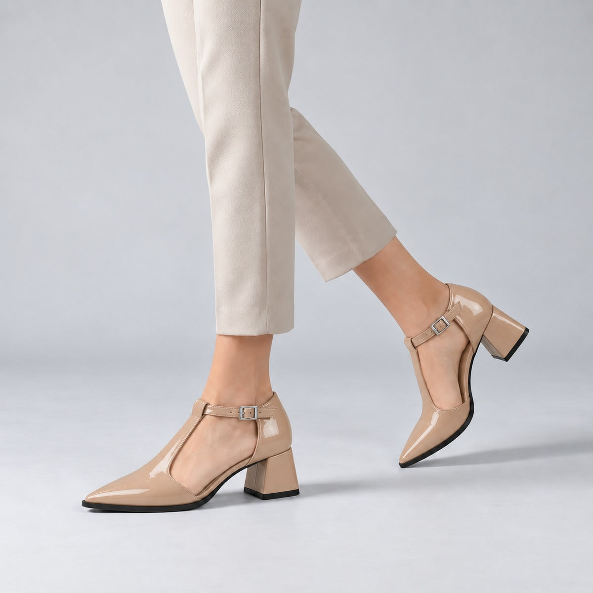 Beige gloss T-strap heels with wide strap, silver buckle and 5 cm flared heel, worn on model, walking — ECADRA