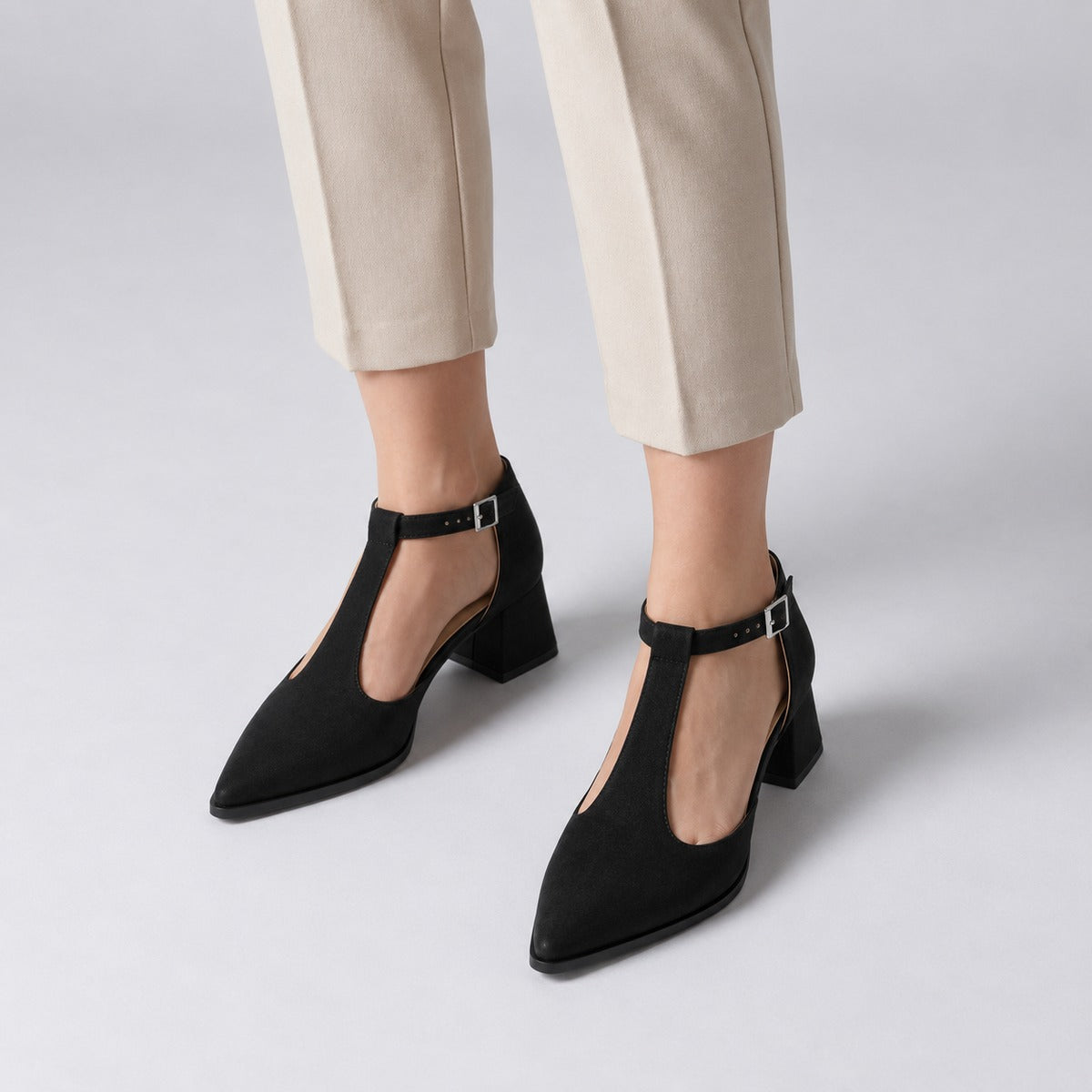Black suede T-strap heels with wide strap, silver buckle and 5 cm flared heel, worn on model, front — ECADRA