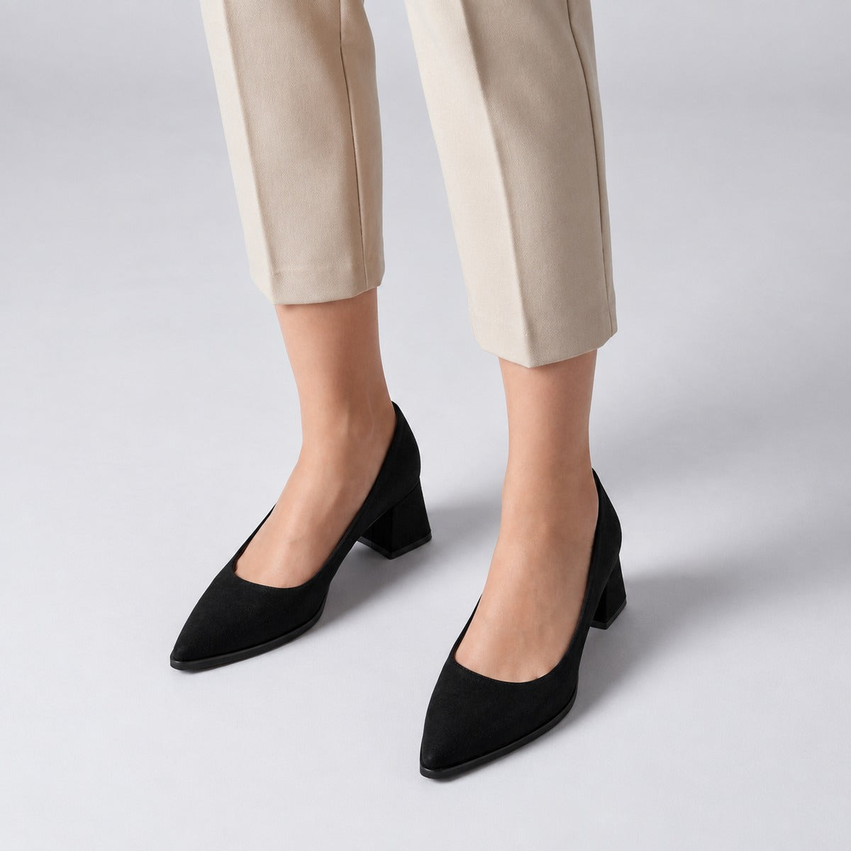 Black suede pointed pump with low 5 cm flared block heel, worn on model, front — ECADRA