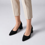 Black suede pointed pump with low 5 cm flared block heel, worn on model, front — ECADRA