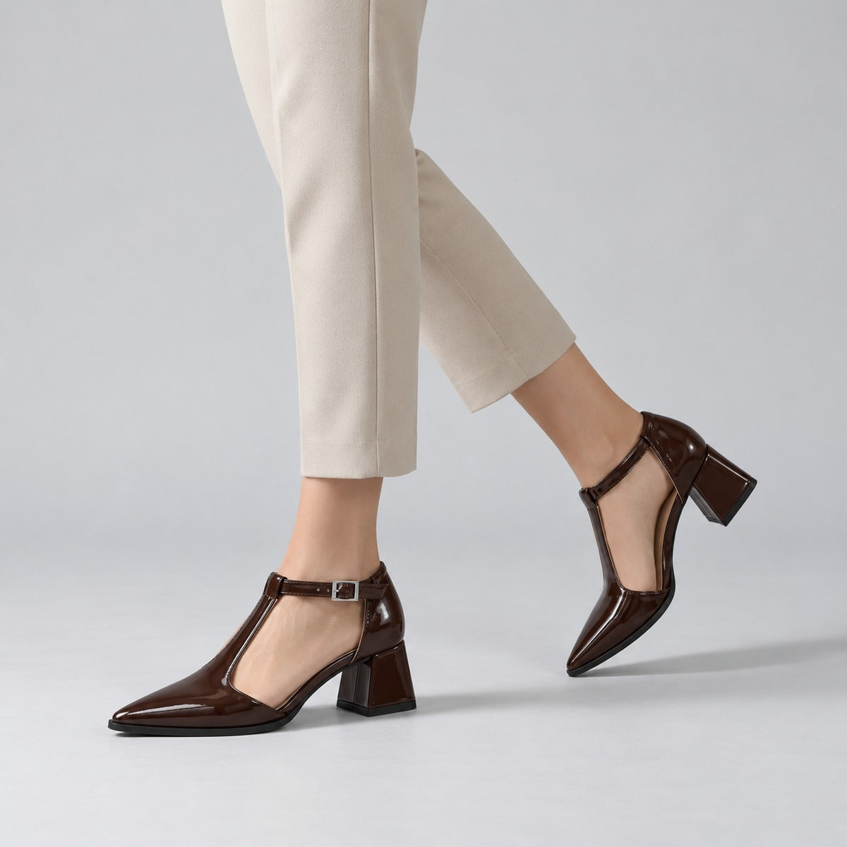 Brown gloss T-strap heels with wide strap, silver buckle and 5 cm flared heel, worn on model, walking — ECADRA