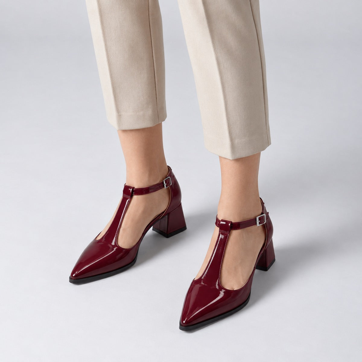 Burgundy gloss T-strap heels with wide strap, silver buckle and 5 cm flared heel, worn on model, front — ECADRA