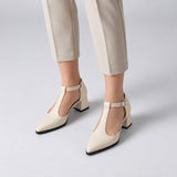 Cream matte T-strap heels with wide strap, silver buckle and 5 cm flared heel, worn on model, front — ECADRA