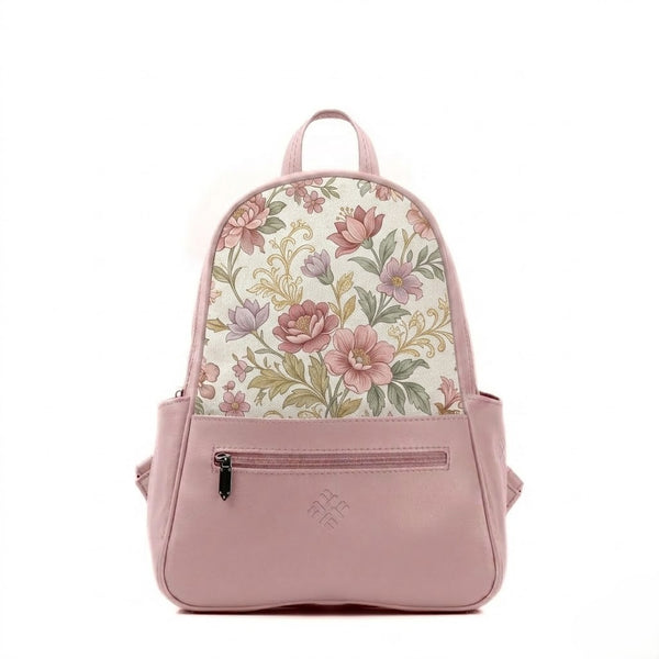 A structured mini backpack with a pink faux leather base and a top flap made of woven fabric printed with a vintage pattern of pink, mauve, and purple flowers with green leaves and gold filigree accents, featuring a front zipper and side pockets.