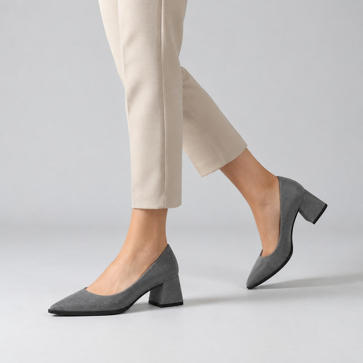 Gray suede pointed pump with low 5 cm flared block heel, worn on model, walking — ECADRA