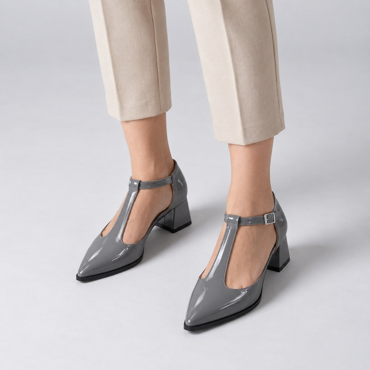 Grey gloss T-strap heels with wide strap, silver buckle and 5 cm flared heel, worn on model, front — ECADRA