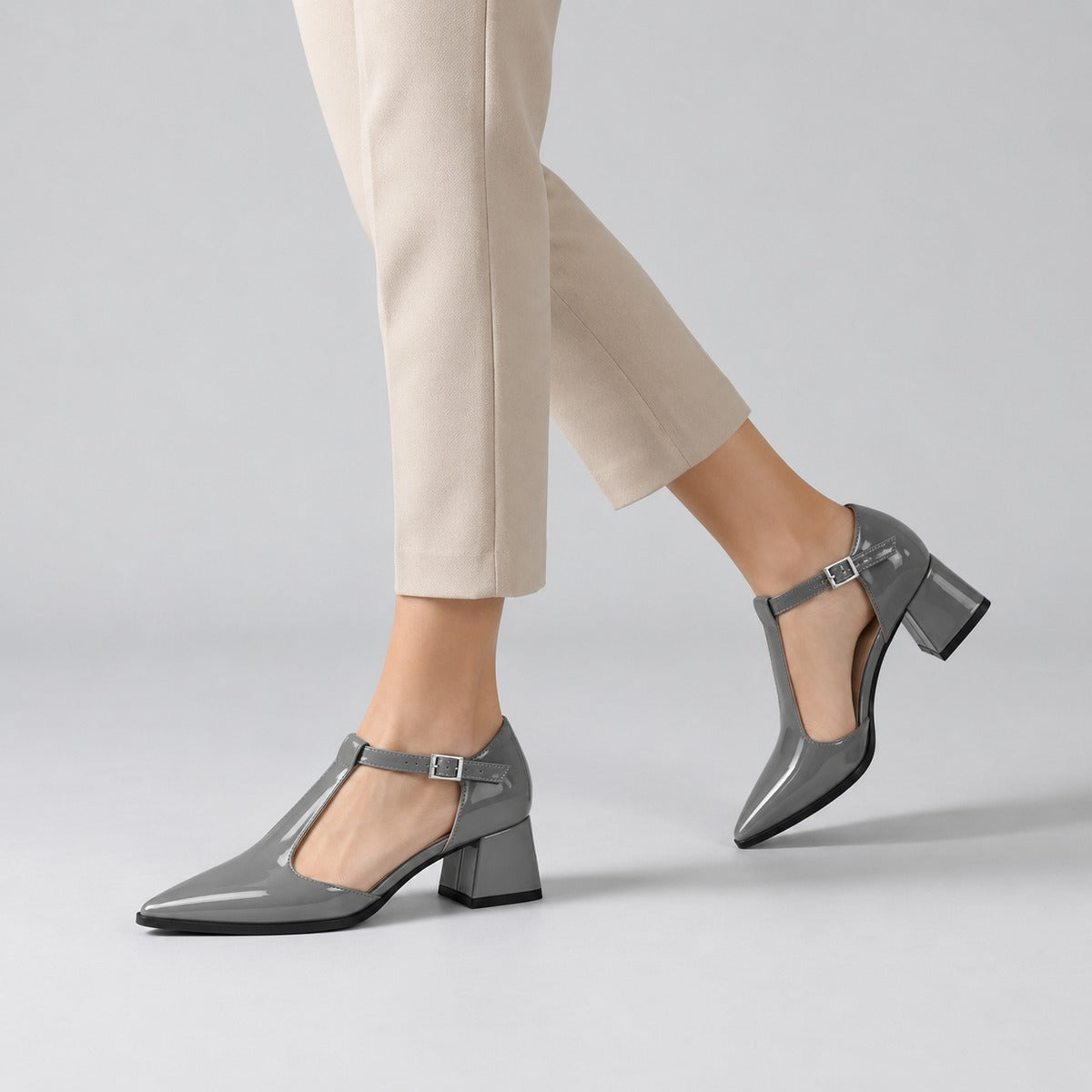 Grey gloss T-strap heels with wide strap, silver buckle and 5 cm flared heel, worn on model, walking — ECADRA