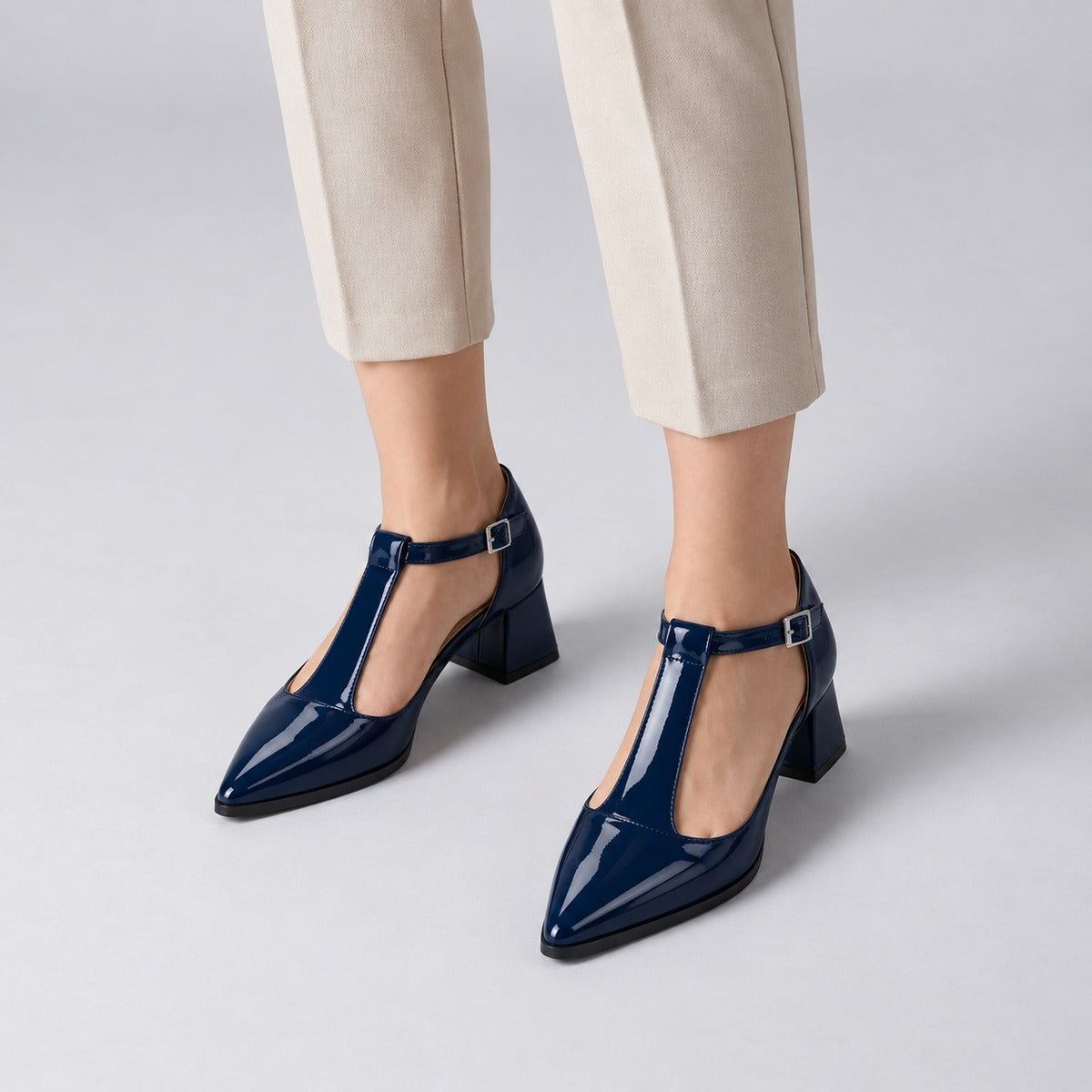 Navy gloss T-strap heels with wide strap, silver buckle and 5 cm flared heel, worn on model, front — ECADRA