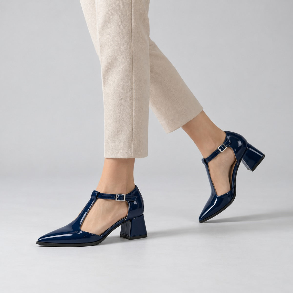 Navy gloss T-strap heels with wide strap, silver buckle and 5 cm flared heel, worn on model, walking — ECADRA
