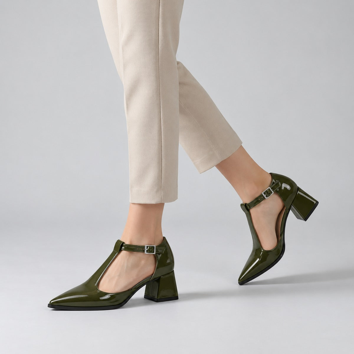 Olive gloss T-strap heels with wide strap, silver buckle and 5 cm flared heel, worn on model, walking — ECADRA