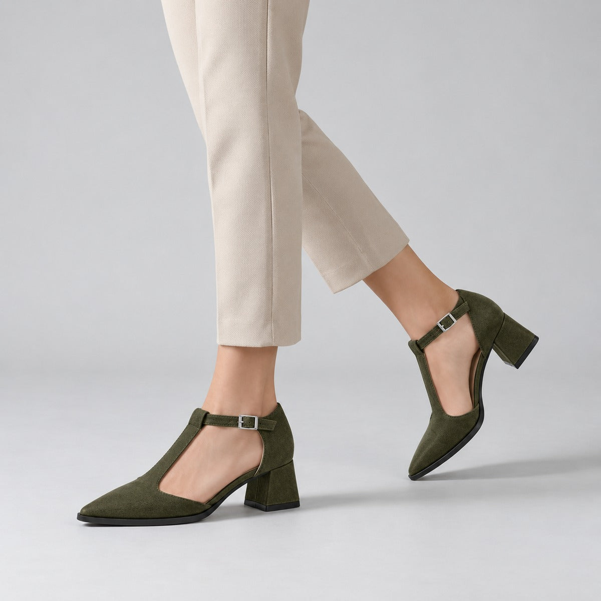 Olive suede T-strap heels with wide strap, silver buckle and 5 cm flared heel, worn on model, walking — ECADRA