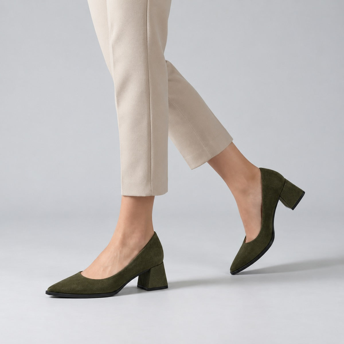 Olive suede pointed pump with low 5 cm flared block heel, worn on model, walking — ECADRA