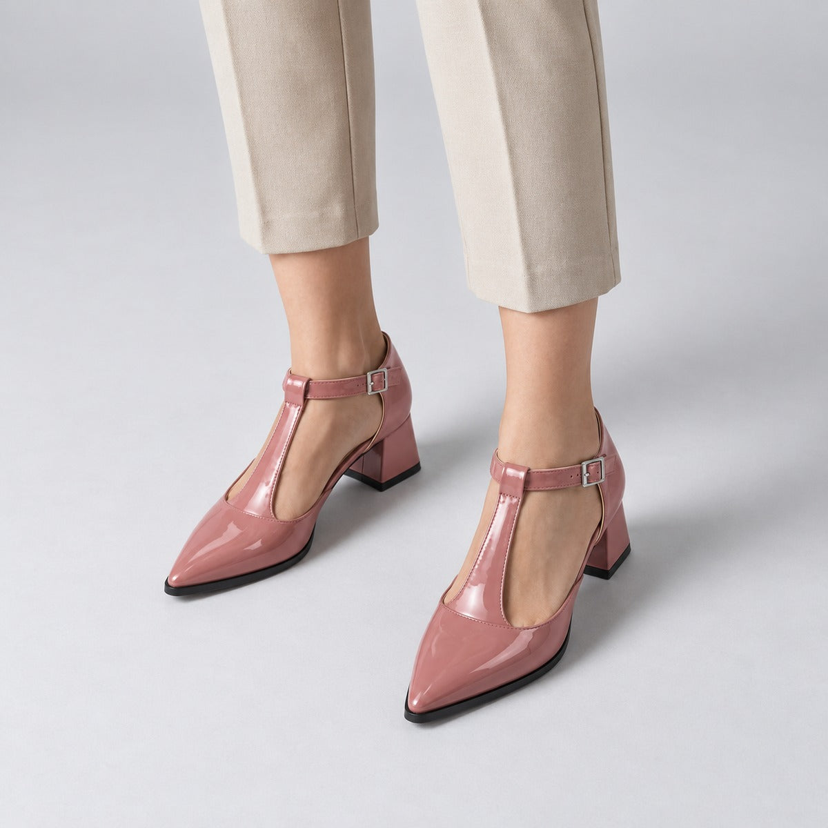 Rose gloss T-strap heels with wide strap, silver buckle and 5 cm flared heel, worn on model, front — ECADRA