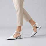 White matte T-strap heels with wide strap, silver buckle and 5 cm flared heel, worn on model, walking — ECADRA
