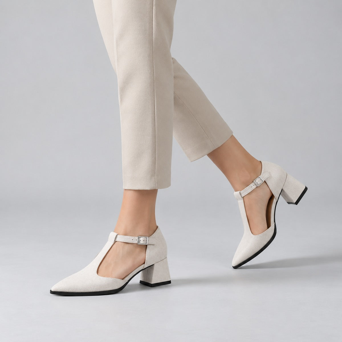 White suede T-strap heels with wide strap, silver buckle and 5 cm flared heel, worn on model, walking — ECADRA