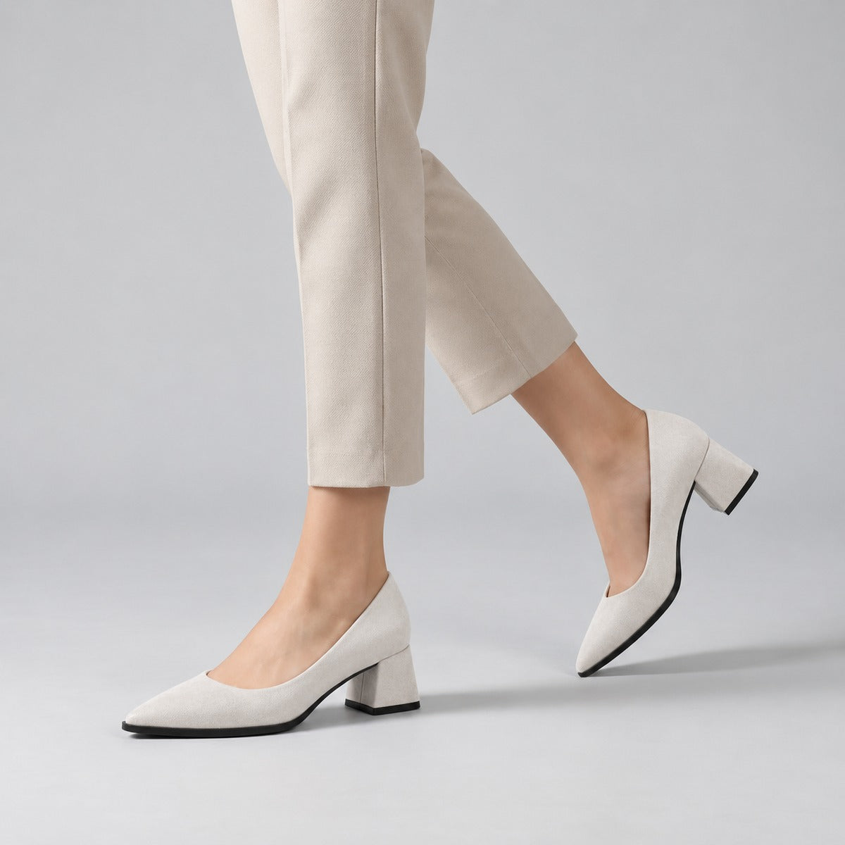 White suede pointed pump with low 5 cm flared block heel, worn on model, walking — ECADRA