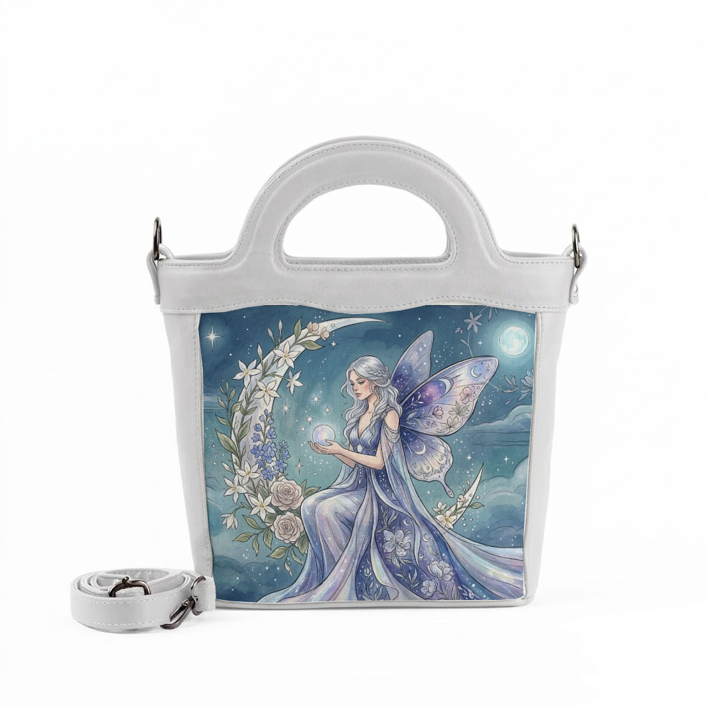 A white handbag in white top.jpg features a beautiful illustration of a fairy with wings sitting on a crescent moon surrounded by flowers, holding a glowing sphere.