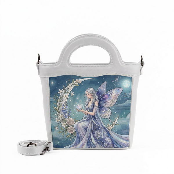 A white handbag in white top.jpg features a beautiful illustration of a fairy with wings sitting on a crescent moon surrounded by flowers, holding a glowing sphere.